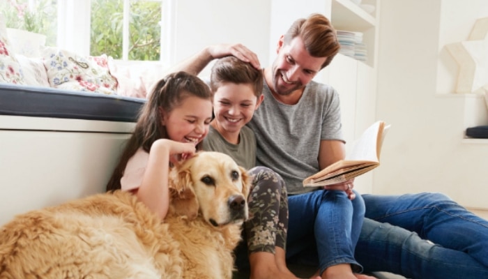 father reading to daughters with dog